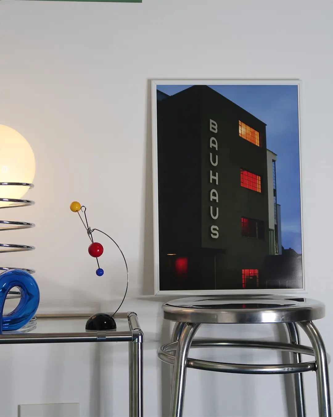 A3サイズのホワイトフレームのバウハウス建築写真ポスター。スツールの上に立てかけられ、機能美あふれるモダンな建築デザインが映えるアートポスター。