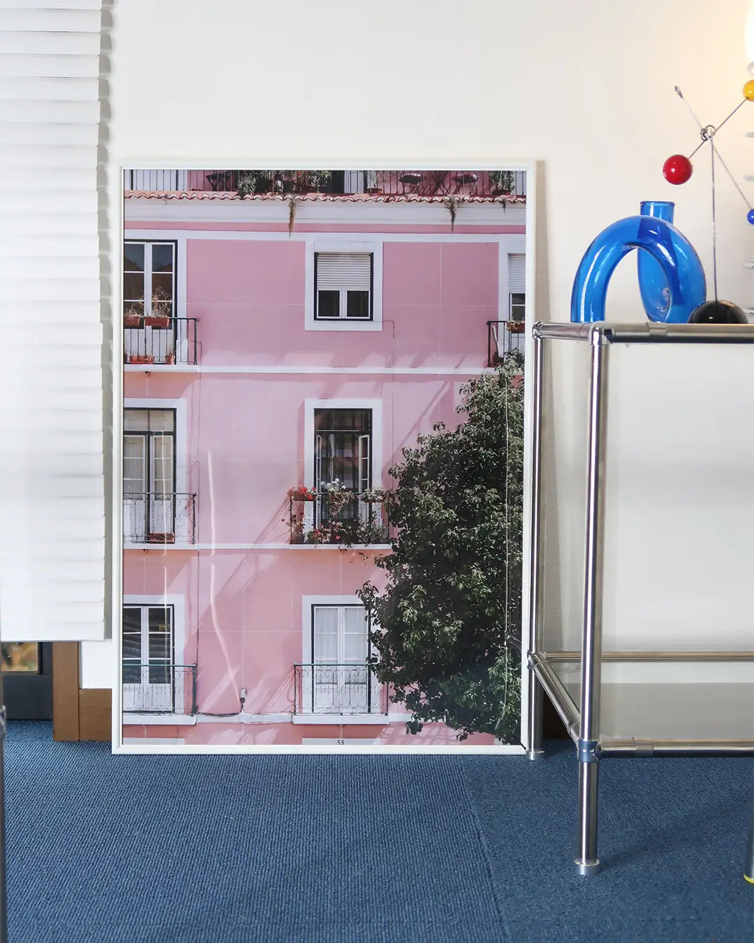 ベッドルームに飾られたホワイトフレームのピンクの建物ポスター。やわらかな色合いが空間に調和するモダンアートポスター