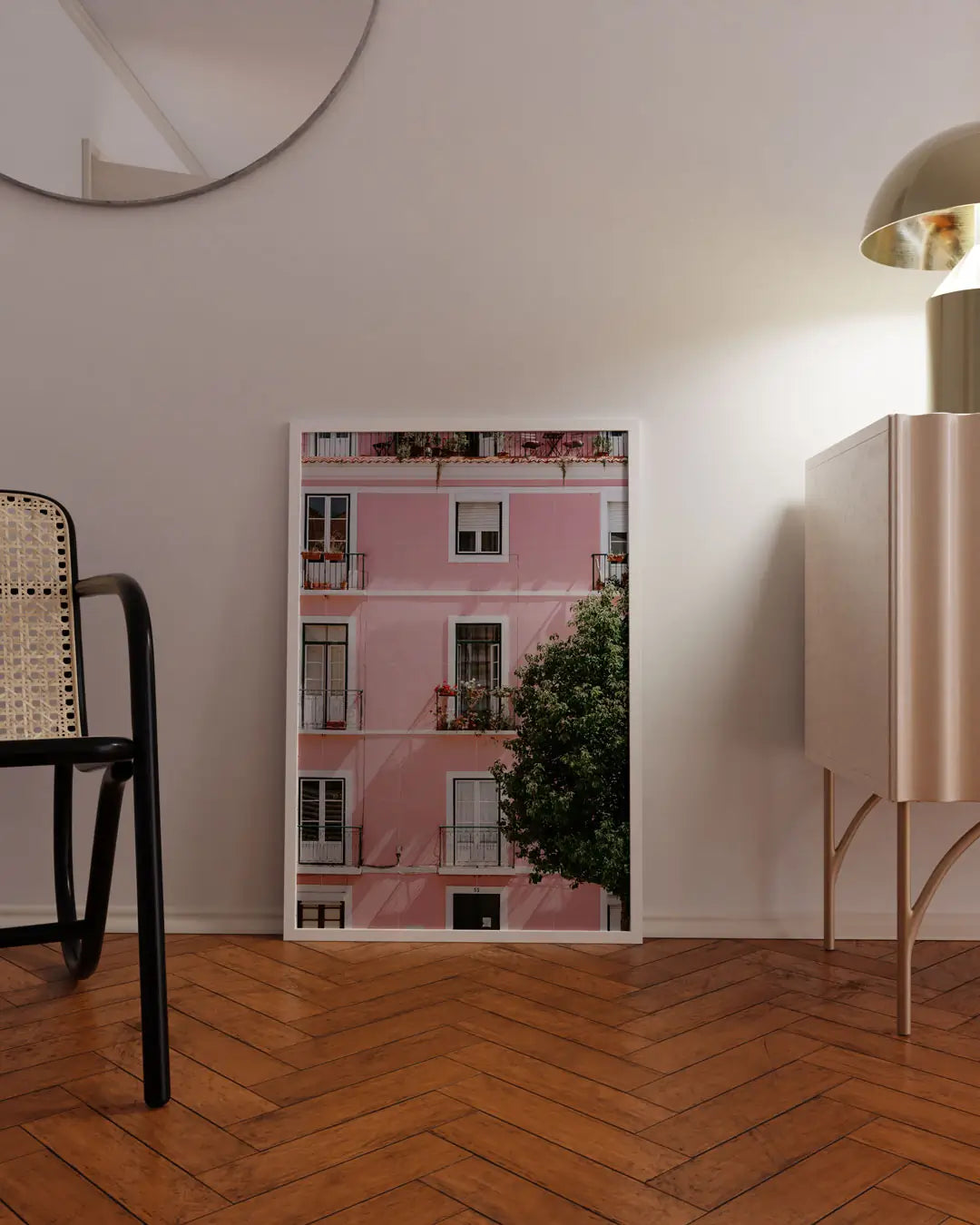 床に立てかけられたホワイトフレームのピンクの建物ポスター。やわらかな色合いが空間に映えるモダンアートポスター。